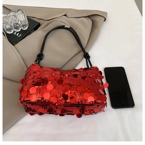 Close-up of vibrant red sequin handbag with woven handle next to a smartphone