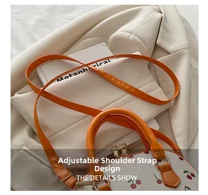 Detail of adjustable orange strap and gold zipper on white cherry print shell bag