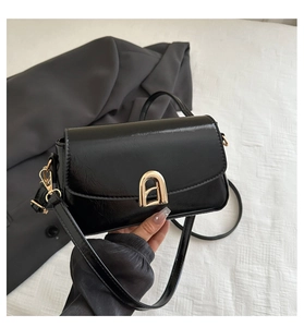 Détail du sac à bandoulière en cuir noir brillant avec boucle en métal doré et lanière