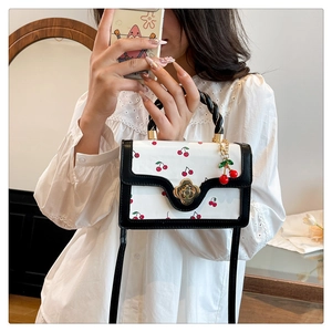 Close-up of cherry print crossbody bag with twist handle and gold petal floral clasp