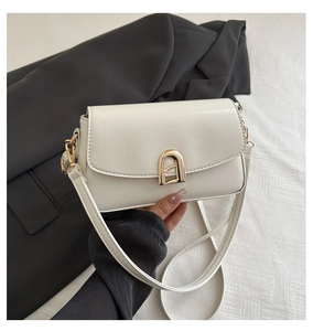 Détail du sac à bandoulière blanc avec un fermoir métallique arqué doré élégant pour femme