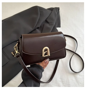 Détail du sac vintage marron foncé en similicuir avec boucle fer à cheval dorée et bandoulière