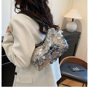 Close-up of stylish silver sequin shoulder bag with black leather strap on a model
