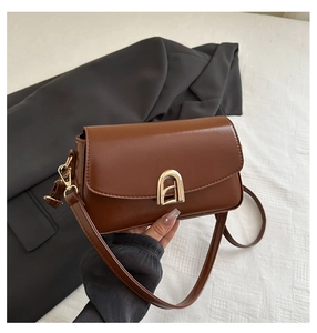Détail d'un sac en cuir PU marron caramel avec boucle dorée en arche et sangle réglable