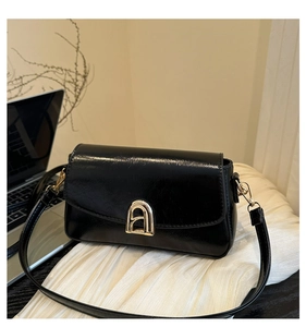 Détail du sac en cuir noir brillant avec boucle géométrique en forme de A dorée