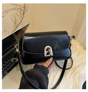 Détail du sac à bandoulière en similicuir noir avec boucle dorée élégante en arche