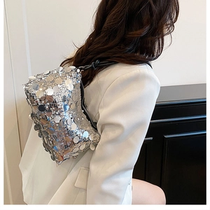 Silver sequin shoulder bag on white blazer, showing reflective texture and metal strap details