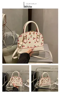 Detail of white cherry print satchel with red contrast edges and gold metal hardware