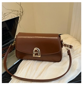 Détail d'un sac bandoulière vintage marron avec une boucle dorée et un fermoir métallique