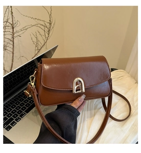 Détail du sac bandoulière en cuir caramel avec boucle en arche dorée et bandoulière fine