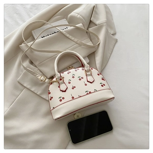 Detailed view of cherry print bucket bag with phone for size comparison