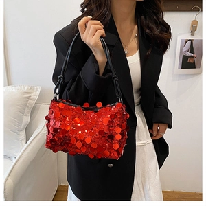 Close-up of vibrant red sequin handbag with chic black handle worn by a model