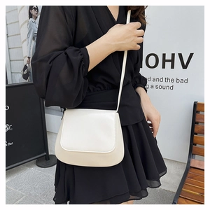 Detail of minimalist creamy white crossbody saddle bag on model for urban commute