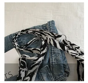 Détail de la sangle en tissu zébré et de l'anneau métallique sur un sac fourre-tout