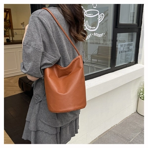 Close-up of caramel leather bucket bag featuring pebbled texture and smooth shoulder strap