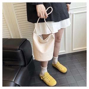 Detail of off-white bucket bag with lychee texture and metal chain accent
