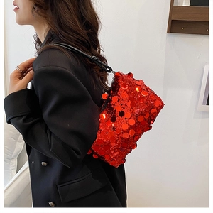 Detailed view of red sequin shoulder bag with black leather knotted strap on a model