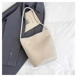 Gros plan d'un sac seau blanc cassé avec texture en cuir grainé sur tissu blanc