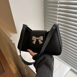Minimalist black faux leather saddle bag with a large silver metal bow buckle detail