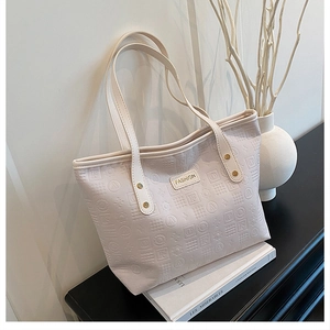 Détails du sac fourre-tout blanc cassé avec motifs embossés et plaque en métal doré