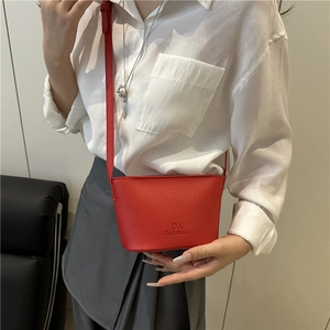 Chic red leather bucket bag with embossed logo and silver floral charm on model
