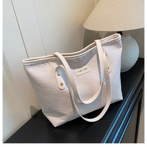Détail du grand sac cabas avec lettres gaufrées en 3D et plaque logo en métal doré