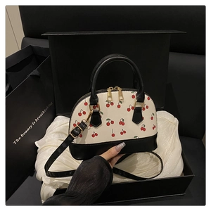 Detail of cherry print shell bag inside a luxury black gift box with white silk lining