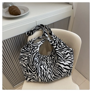 Grand sac cabas en toile à motif zèbre minimaliste posé sur une chaise blanche élégante