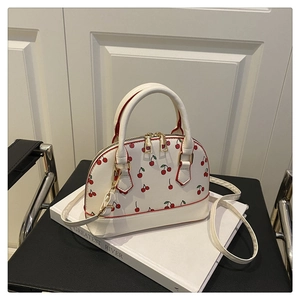 Detail of white shell bucket bag with red cherry prints and gold-tone zipper hardware