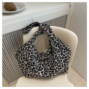 Détail du sac cabas en toile à motif léopard noir et blanc posé sur une chaise blanche