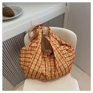 Détail du sac fourre-tout en toile à carreaux jaunes avec anneau en métal sur chaise
