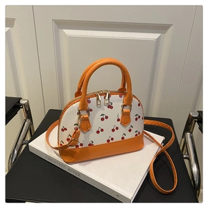 Close-up of cherry print bucket bag with orange leather trim on a lifestyle book