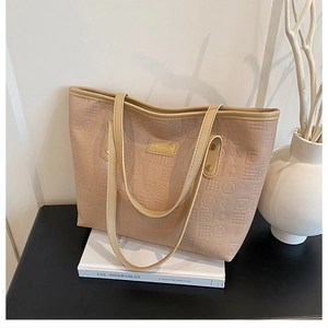 Detail of beige embossed tote bag with FASHION label and gold rivets on a white book