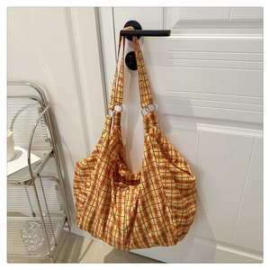 Détail du cabas à carreaux orange avec anneaux métalliques et texture de tissu plissé