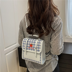 Mini blue plaid canvas backpack with apple embroidery shown on a person's back