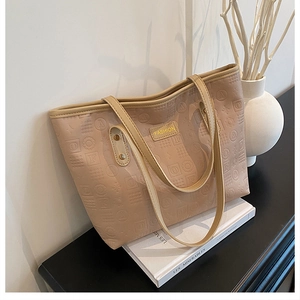 Détail du cabas en similicuir beige avec motifs géométriques gaufrés et étiquette mode
