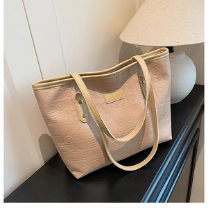 Détail du sac cabas rose avec lettres gaufrées et étiquette de mode sur un bureau