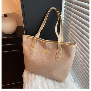 Close-up of beige tote bag with embossed letters and gold FASHION metal logo