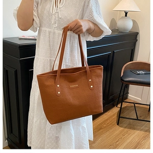 Détail d'un sac cabas marron en similicuir avec motif géométrique et logo en métal