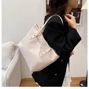 Detail of off-white tote bag with embossed geometric patterns and fashion metal plate