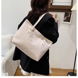 Detail of cream white tote bag featuring embossed geometric patterns and fashion tag