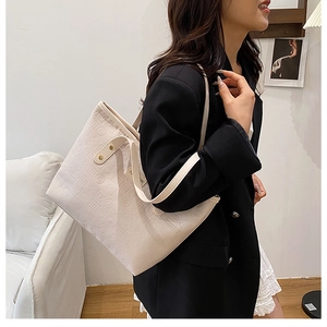 Detail of cream oversized tote bag with embossed letter texture and shoulder strap
