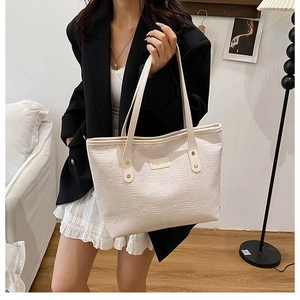Détail du sac cabas blanc crème avec gaufrage géométrique et logo en métal doré