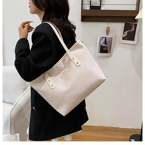 Détail du cabas blanc cassé avec texture gaufrée en 3D et étiquette de mode en cuir marron