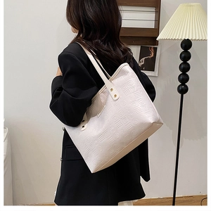Détail du sac cabas crème avec motifs géométriques gaufrés et ferrures dorées