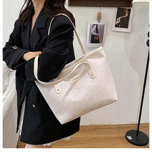 Détail du sac cabas en cuir PU blanc avec motifs géométriques gaufrés et logo en métal