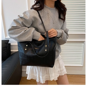 Gros plan d'un sac cabas en cuir noir gaufré avec logo doré et motifs géométriques