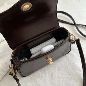 Sac baguette en cuir verni marron foncé avec fermoir doré et essentiels du quotidien