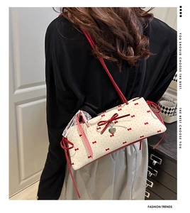 Détail d'un sac seau matelassé crème avec nœuds rouges et pendentif en cœur