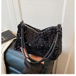 Close-up of black sequined crossbody bag with twisted leather handle and shiny texture